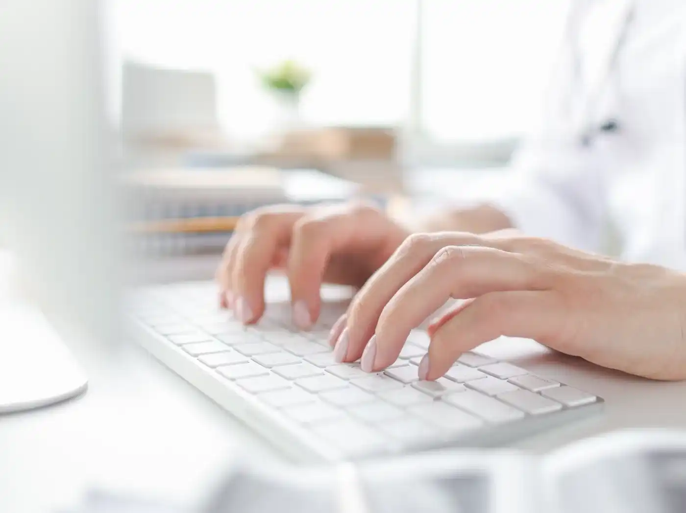 Eine Person in medizinischer Kleidung sitzt in einer Art Büro und arbeitet mit einer Tastatur