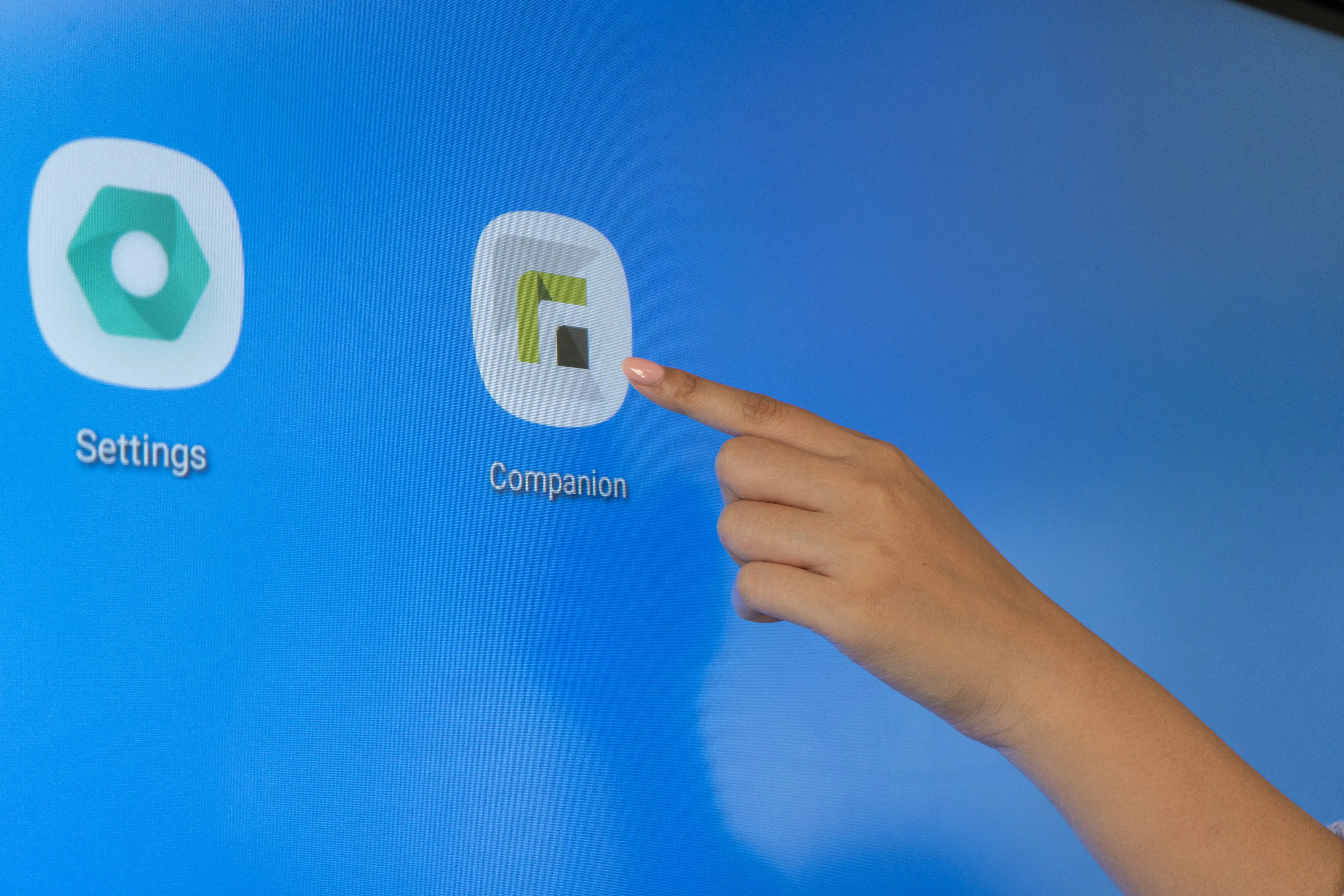 Eine Hand deutet mit dem Zeigefinger auf das Icon des Relution Companion, welches auf einem großen Whiteboard abgebildet ist