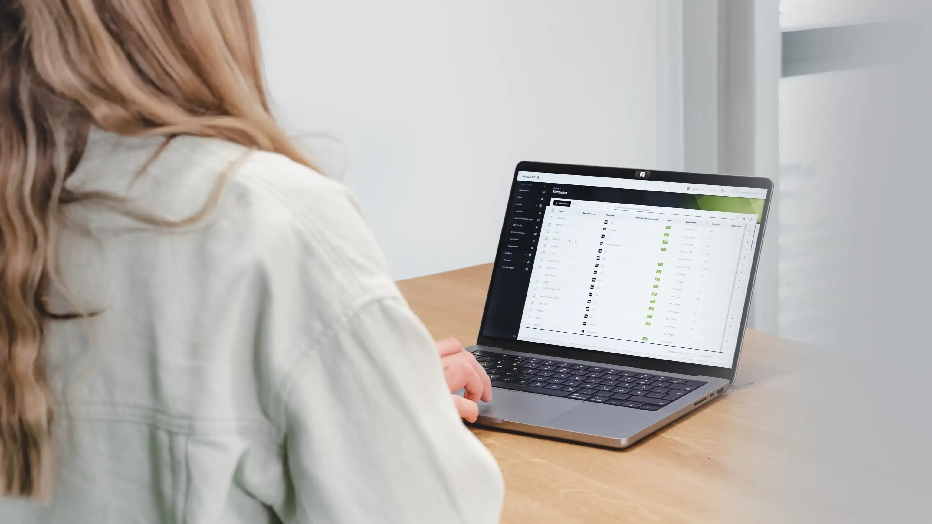 Eine Person sitzt mit dem Rücken zum Betrachter, sie sitzt vor einem macBook, auf dem das Relution Portal angezeigt wird