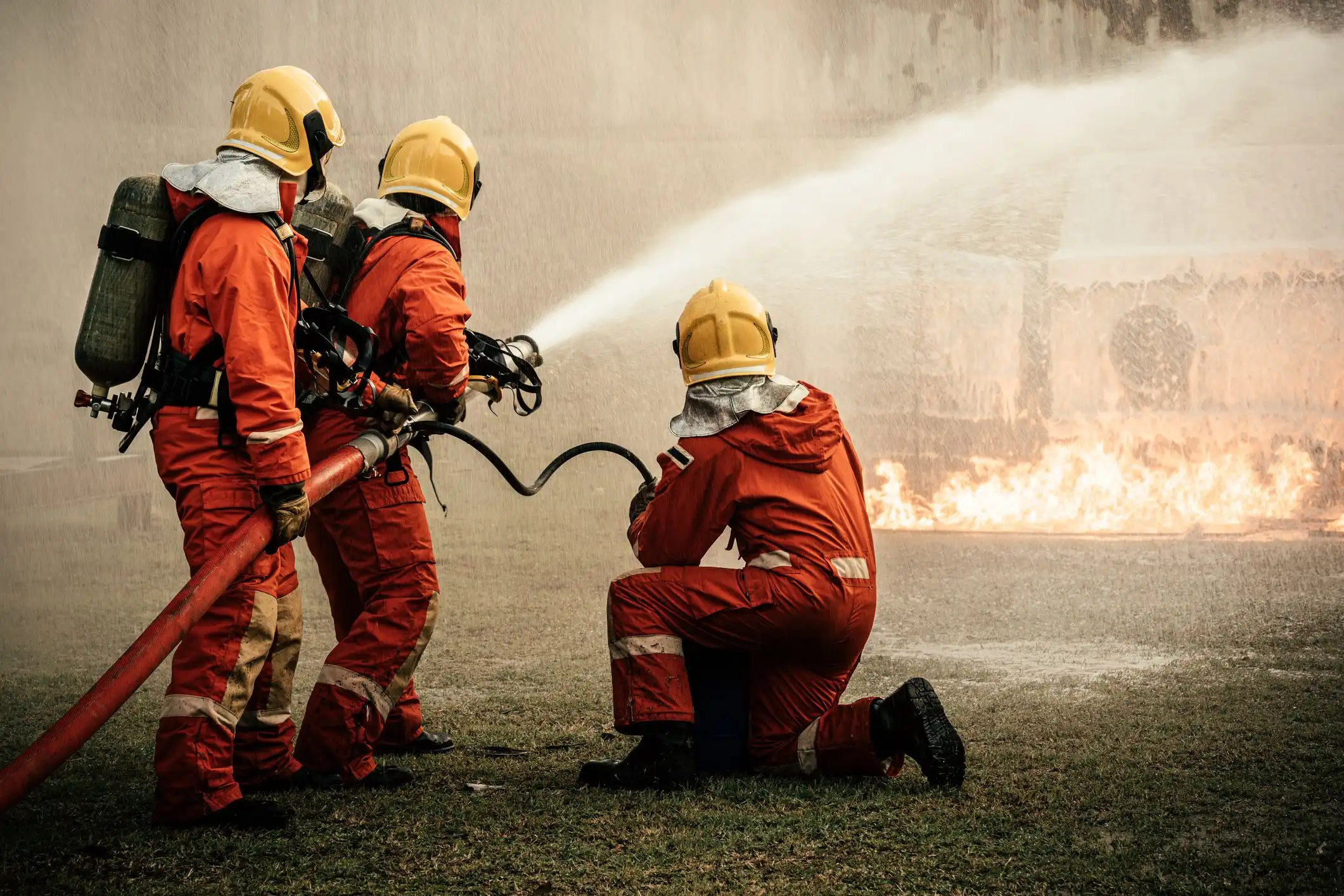 Drei Feuerwehrleute löschen zusammen ein Feuer