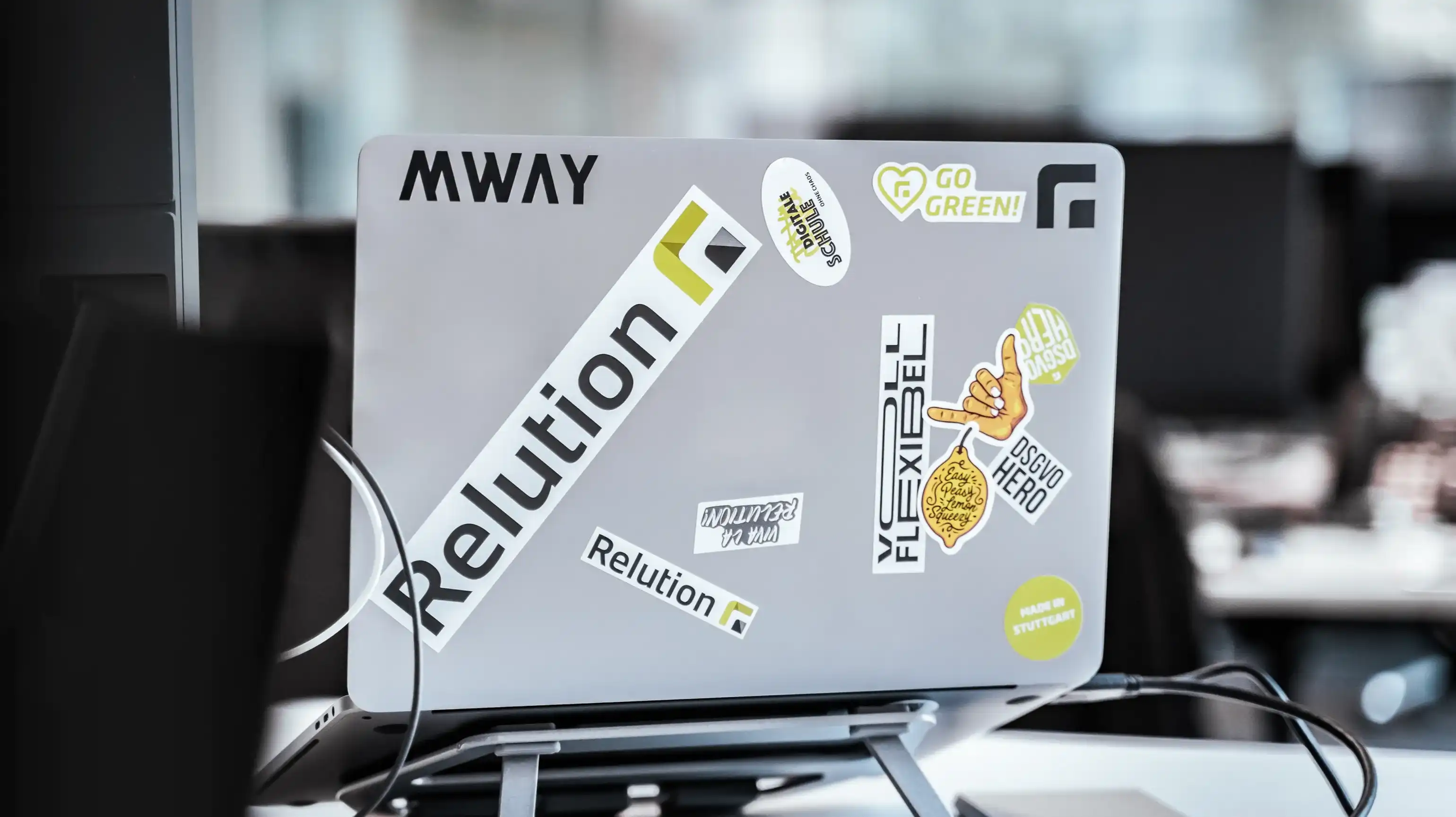 Die Rückseite eines aufgeklappten Laptops ist zu sehen, auf dem Laptop sind zahlreiche Aufkleber von Relution zu sehen