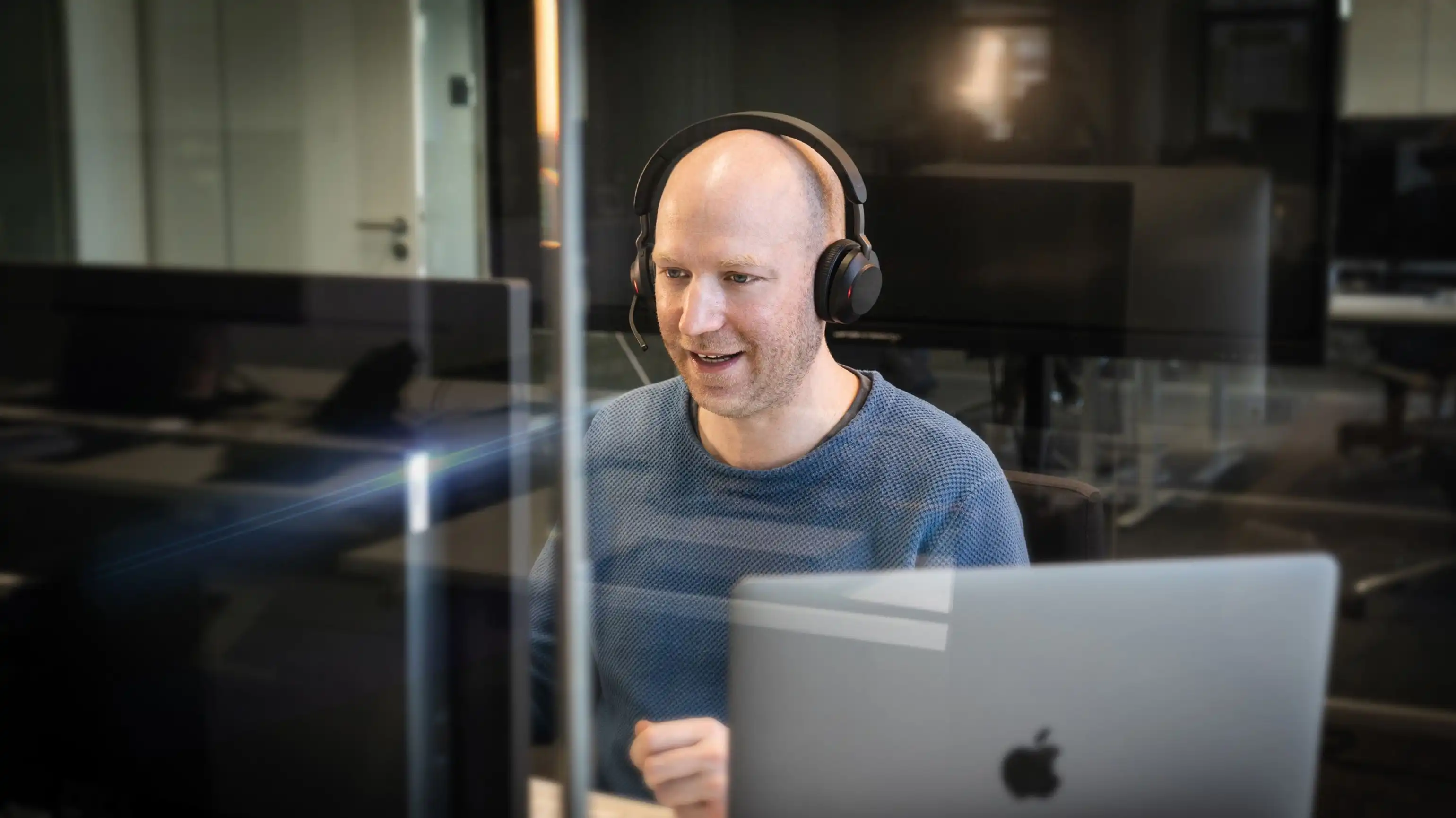 Relution Mitarbeiter Hanno Polomsky trägt ein Headset, blickt auf zwei Bildschirme und scheint zu sprechen